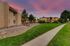 Charming apartment community with lush green pathways, beautifully lit at sunset, offering a serene and inviting atmosphere.