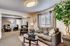 Inviting living room with elegant decor, featuring a plush gray sofa, stylish armchairs, and abundant natural light through large windows. Perfect for relaxing and entertaining.