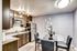 Contemporary kitchen and dining area with sleek dark wood cabinets, stainless steel appliances, and a stylish glass dining table with plush chairs.