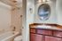 Elegant apartment bathroom featuring a modern vanity with a round mirror, and a combination bathtub and shower.