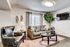 Cozy living room with plush beige sofa, elegant leather chair, stylish decor, and a large window bringing in natural light.