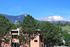 Charming apartment building nestled in lush greenery with breathtaking mountain views.