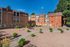 Charming apartment complex exterior with modern brick facade set against a clear blue sky, featuring well-maintained landscaping and tranquil outdoor seating.