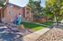 Charming apartment complex exterior with lush green lawns, mature trees, and decorative flags, exuding a welcoming and serene atmosphere.