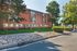 Charming red-brick apartment building surrounded by lush greenery and a well-maintained rock garden, offering serene and inviting living in a peaceful neighborhood.
