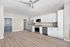Contemporary kitchen and living area featuring sleek white cabinetry, modern appliances, and elegant wood flooring. Perfect for stylish urban living.