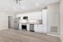 Modern kitchen with sleek white cabinetry, stainless steel appliances, and spacious hardwood flooring ready for entertaining.