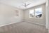 Bright and airy bedroom with soft carpet, ceiling fan, and scenic window views of the surrounding hills.