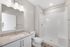 Modern bathroom with sleek vanity, large mirror, and spacious glass-enclosed shower, ideal for a luxurious lifestyle.