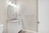 Elegant bathroom featuring a sleek white vanity with a large mirror, under stylish lighting, exuding a modern and clean aesthetic.
