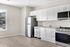 Bright modern kitchen with sleek stainless steel appliances, white cabinets, and a large window offering a scenic view.