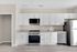 Modern apartment kitchen with sleek white cabinets, stainless steel appliances, and spacious countertops.