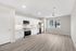 Bright modern kitchen and living area with sleek white cabinetry, stainless steel appliances, and elegant wood flooring, offering a spacious and inviting atmosphere.