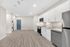 Sleek modern kitchen with stainless steel appliances, elegant white cabinetry, and wood-style flooring, leading to a cozy laundry nook.
