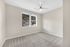 Bright, airy bedroom with soft carpet, modern ceiling fan, and window showcasing picturesque hillside views.