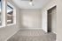 Bright and airy bedroom with plush carpet, large windows offering serene views, and a spacious closet.