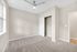 Bright bedroom with plush carpet, large window, sleek ceiling fan, and spacious closet.