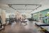 Bright and spacious gym featuring a variety of modern exercise equipment, including treadmills, dumbbells, and resistance machines, with large windows providing ample natural light.