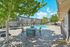Sunny apartment complex courtyard featuring a sparkling pool, lounge chairs, and shaded seating under lush trees.