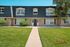 Charming two-story building with elegant mansard roof and manicured lawn, perfect for modern living.