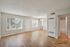 Bright and airy living space with large windows, wood flooring, and modern chandelier in The Chateau Apartments.