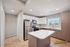 Modern kitchen with sleek cabinetry, stainless steel appliances, and a large island in a bright, airy apartment setting with mountain views.