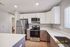 Modern kitchen with sleek white cabinetry, stainless steel appliances including a refrigerator and oven, elegant countertops, and a built-in microwave.