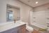 Modern bathroom featuring a sleek vanity with a spacious countertop, large mirror, and inviting bathtub at The Chateau Apartments.