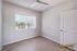 Bright bedroom with modern ceiling fan and large window offering scenic views, featuring sleek wood flooring and minimalist design.