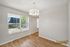 Bright dining area with modern chandelier, large window with natural light, and elegant wood flooring.
