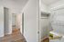 Bright interior showcasing a modern laundry area with sleek wood flooring, leading into a spacious hallway.