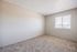 Bright and airy bedroom with fresh carpet, neutral walls, and a large window offering scenic views, perfect for relaxation.