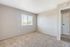 Bright and spacious bedroom with plush carpet and a large window offering scenic views, perfect for relaxation and comfort.