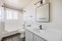 Modern bathroom with sleek fixtures, elegant vanity, and stylish mirror under bright natural light.
