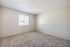 Bright and airy empty room with plush carpet and large window, ideal for customization and personal style.
