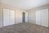 Spacious bedroom with plush carpet flooring and dual closets, offering ample storage and comfort.