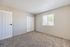 Bright and airy bedroom with plush carpeting, large window, and ample closet space offering a cozy retreat.