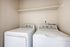 Modern laundry room with a sleek washer and dryer set, complemented by a convenient overhead shelf.