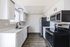 Modern kitchen with sleek stainless steel appliances, elegant white cabinetry, and stylish wood flooring.