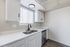 Bright, modern kitchen with sleek white cabinetry, stainless steel appliances, and large window for natural light.