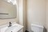 Modern bathroom with elegant fixtures, featuring a sleek mirror and contemporary lighting.