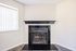Chic apartment corner with a sleek black tile fireplace and a modern mantel, complemented by natural light from vertical blinds.