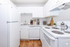 Charming kitchen with sleek white cabinetry, modern appliances, and elegant hardwood flooring.