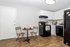 Charming kitchen area featuring sleek white cabinetry, modern appliances, and cozy bistro dining set on beautiful hardwood floors.
