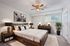 Elegant bedroom with a rustic wooden bed frame, cozy neutral decor, and modern ceiling fan, creating a serene retreat.