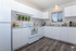 Bright and modern kitchen with sleek white cabinets, stylish plants, and contemporary appliances.