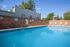 Inviting outdoor pool area with crystal-clear water, surrounded by lush greenery and comfortable lounge chairs, ideal for relaxation and leisure.