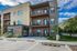 Modern apartment building with sleek design, featuring private balconies and lush landscaping, set against a stunning mountain backdrop.