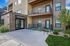 Modern apartment building entrance with stylish architecture, featuring a welcoming glass door and vibrant landscaped garden.