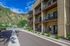Modern apartment building with spacious balconies and stunning mountain views, surrounded by lush greenery.